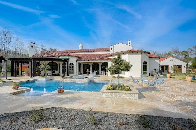 rear view of property featuring pool water feature, a swimming pool with hot tub, and a patio area