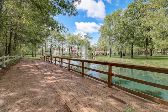 view of dock with a deck with water view and a lawn