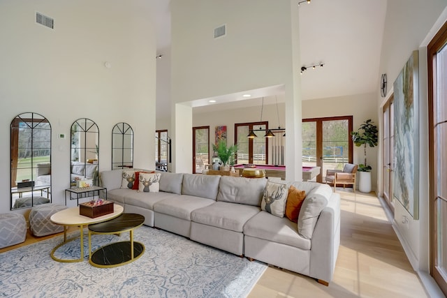 living room featuring french doors, light hardwood / wood-style floors, and a high ceiling