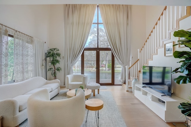 living room featuring light hardwood / wood-style flooring, a high ceiling, and french doors