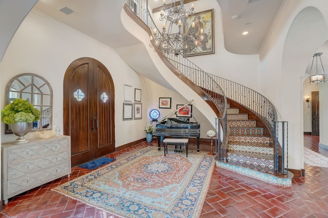 foyer featuring ornamental molding, a high ceiling, and an inviting chandelier