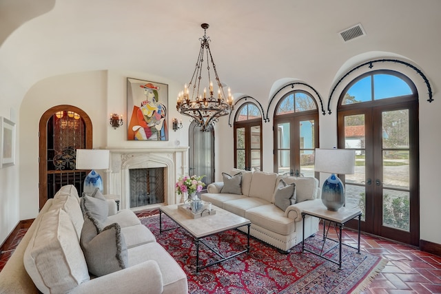 living room featuring french doors, a towering ceiling, and a notable chandelier