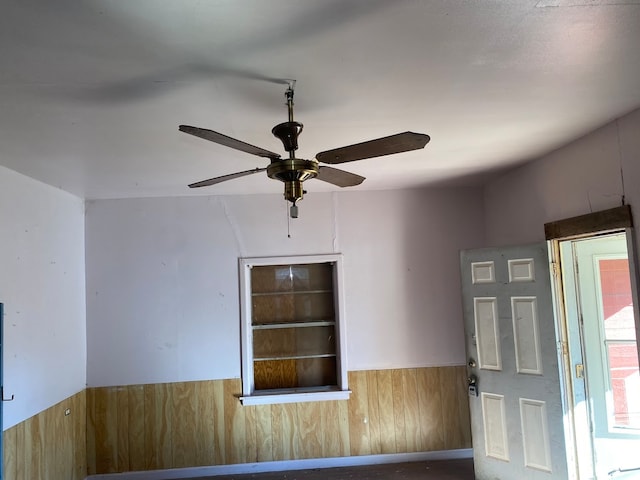 empty room with wooden walls and ceiling fan