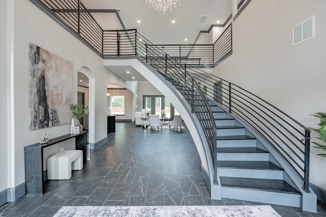 staircase with a towering ceiling and an inviting chandelier