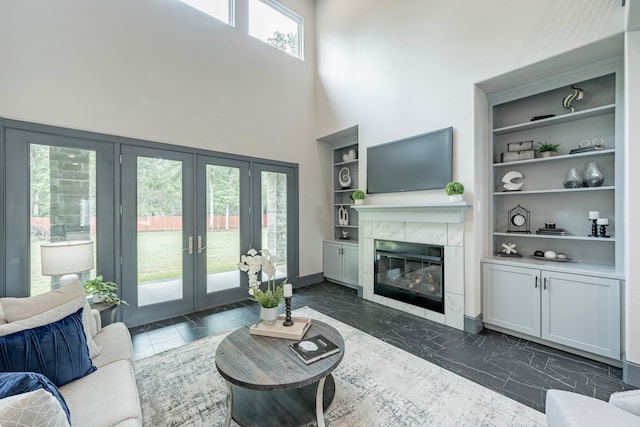 living room featuring french doors, built in features, and a healthy amount of sunlight