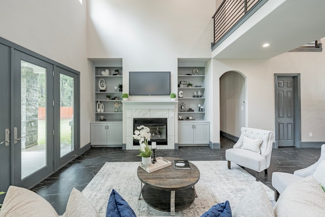 living room featuring a fireplace, built in features, and a high ceiling