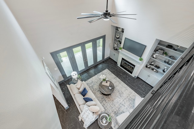 living room with ceiling fan, dark wood-type flooring, and a high ceiling