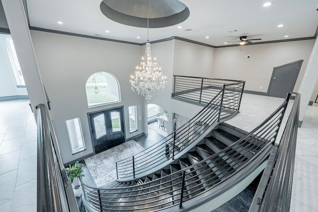 staircase featuring ceiling fan with notable chandelier, crown molding, and a high ceiling