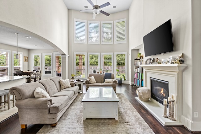 living room featuring ceiling fan, dark hardwood / wood-style floors, and a high ceiling