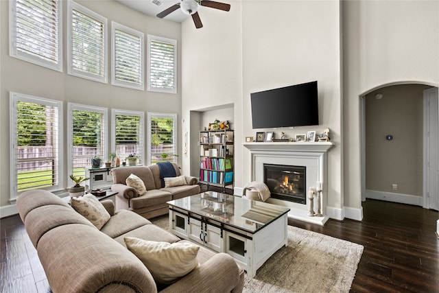 living room with ceiling fan, dark hardwood / wood-style floors, and a high ceiling