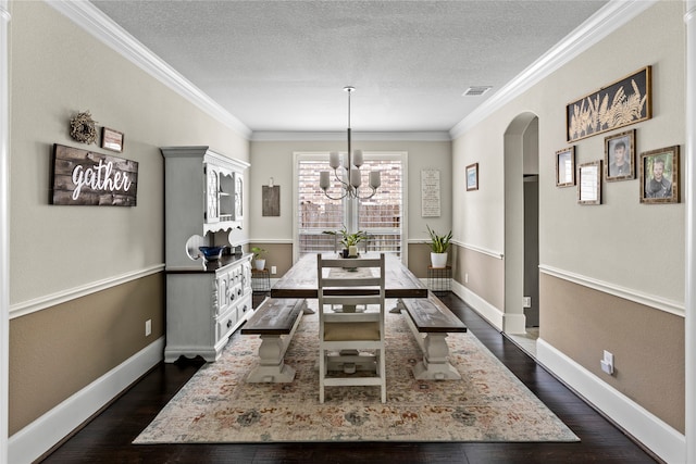 dining room featuring dark wood-type flooring, ornamental molding, a notable chandelier, and a textured ceiling