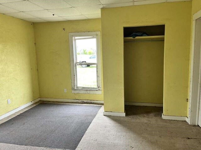 300 E Curtis St, Quanah, TX 79252 - unfurnished bedroom featuring carpet floors, baseboards, a drop ceiling, and a closet