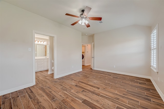 unfurnished bedroom featuring washer / dryer, wood-type flooring, ceiling fan, and ensuite bath