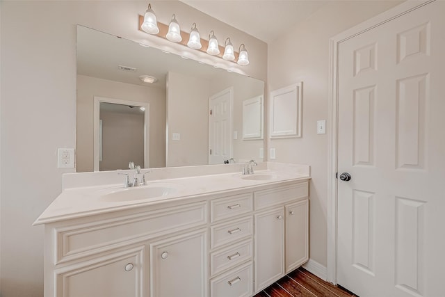 8705 Rowen Ct, Needville, TX 77461 - bathroom with double vanity, a sink, wood finished floors, and visible vents