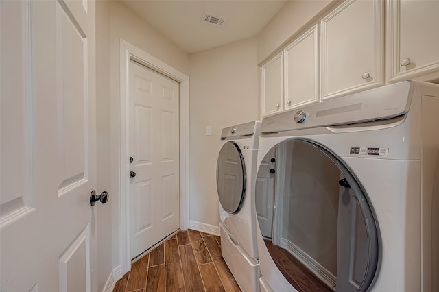 laundry area with cabinets, washing machine and dryer, and hardwood / wood-style flooring