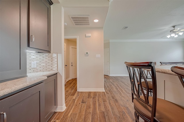 8705 Rowen Ct, Needville, TX 77461 - kitchen with light wood finished floors, gray cabinets, tasteful backsplash, a ceiling fan, and baseboards