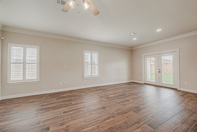 empty room with crown molding, wood-type flooring, ceiling fan, and a wealth of natural light