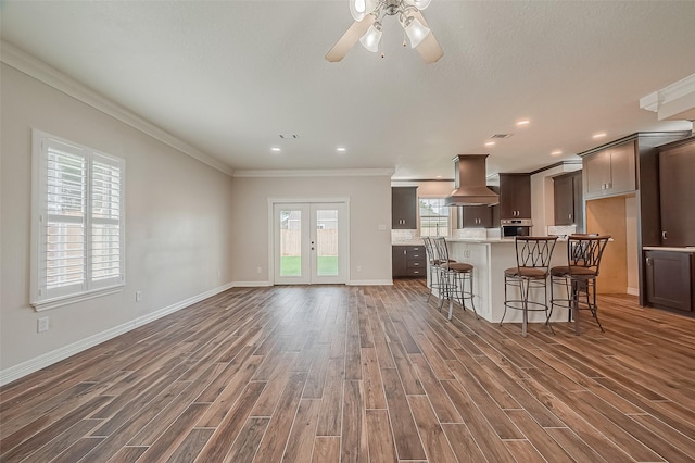 8705 Rowen Ct, Needville, TX 77461 - kitchen featuring wood finished floors, ornamental molding, island exhaust hood, a ceiling fan, and stainless steel oven
