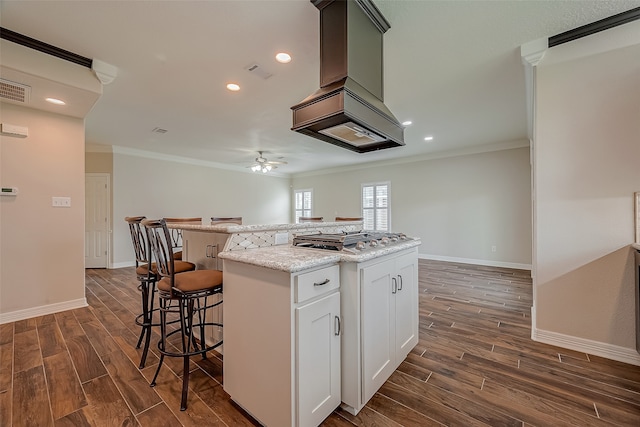 kitchen with white cabinetry, stainless steel gas cooktop, dark hardwood / wood-style floors, ceiling fan, and a kitchen island