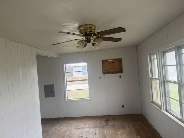 spare room featuring wood walls, electric panel, ceiling fan, and dark hardwood / wood-style floors