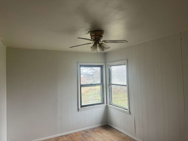 spare room featuring ceiling fan, wood walls, and light hardwood / wood-style floors