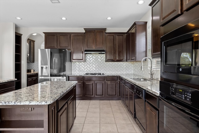 kitchen featuring black appliances, dark brown cabinets, a center island, and sink