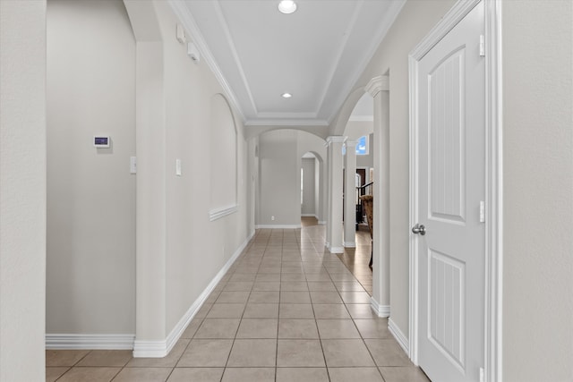 hall featuring decorative columns, ornamental molding, and light tile patterned flooring