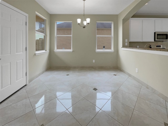 unfurnished dining area featuring light tile patterned floors, a chandelier, and sink