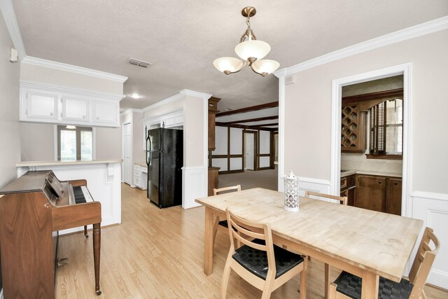 dining area featuring ornamental molding, a chandelier, light hardwood / wood-style floors, and a textured ceiling