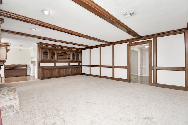 unfurnished living room with ornamental molding, beamed ceiling, and light colored carpet