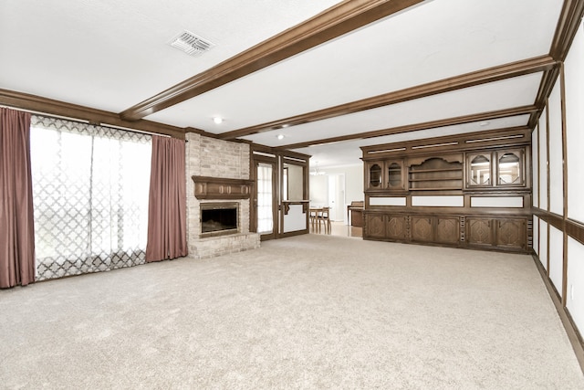 unfurnished living room with a brick fireplace, crown molding, beamed ceiling, and light colored carpet