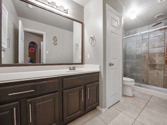 bathroom featuring toilet, walk in shower, tile patterned flooring, vanity, and a textured ceiling