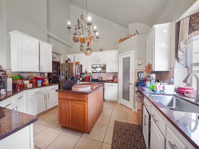 kitchen featuring high vaulted ceiling, white cabinetry, a center island, an inviting chandelier, and appliances with stainless steel finishes