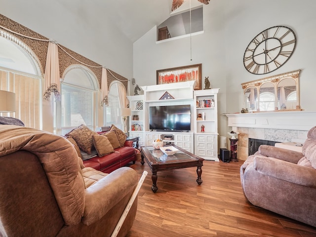 living room with high vaulted ceiling, wood-type flooring, and a tile fireplace