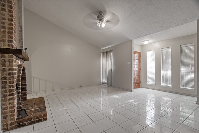 tiled empty room with ceiling fan, vaulted ceiling, and a textured ceiling