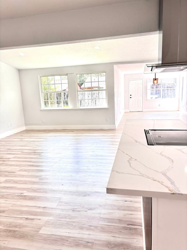 kitchen featuring ventilation hood, light hardwood / wood-style flooring, and light stone countertops