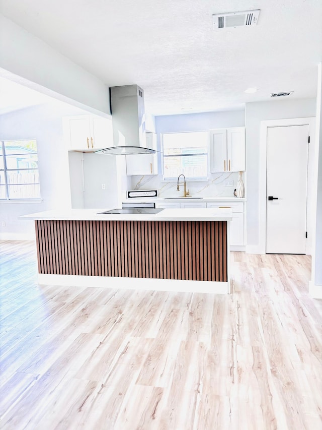 kitchen with a healthy amount of sunlight, exhaust hood, and white cabinetry