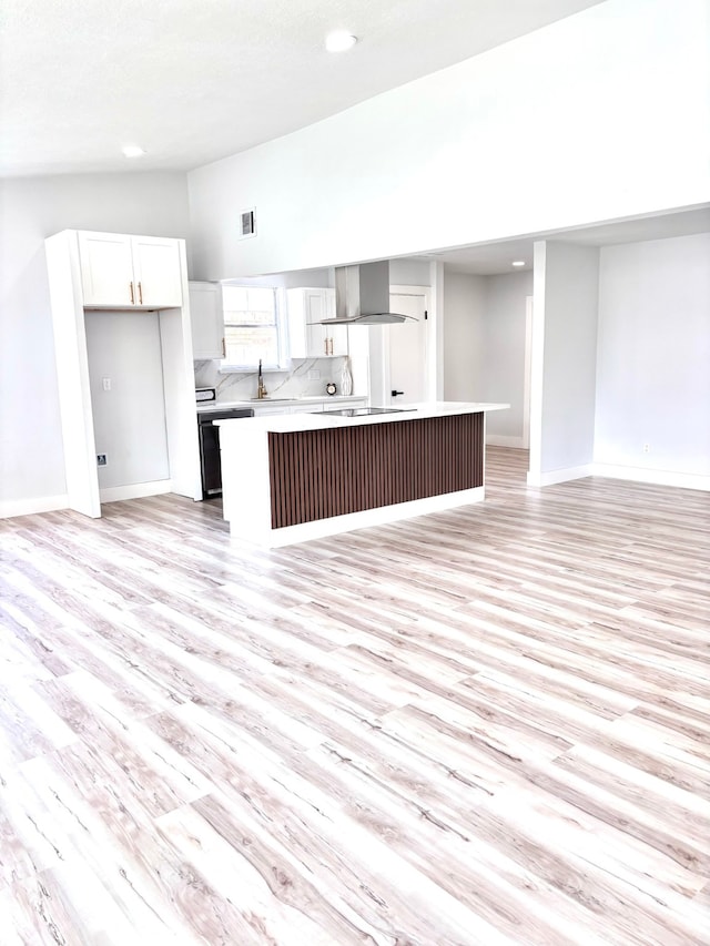 kitchen featuring light wood-type flooring, wall chimney exhaust hood, a center island, and white cabinets