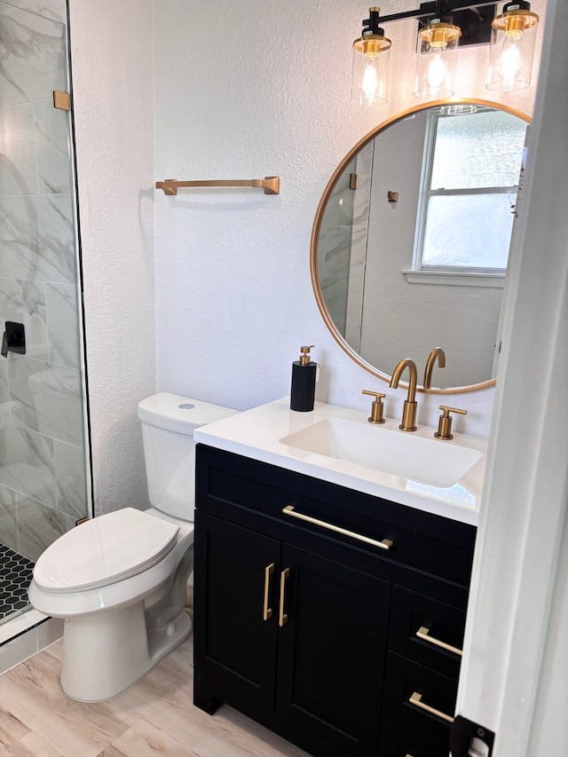 bathroom with vanity, toilet, wood-type flooring, and a shower with shower door