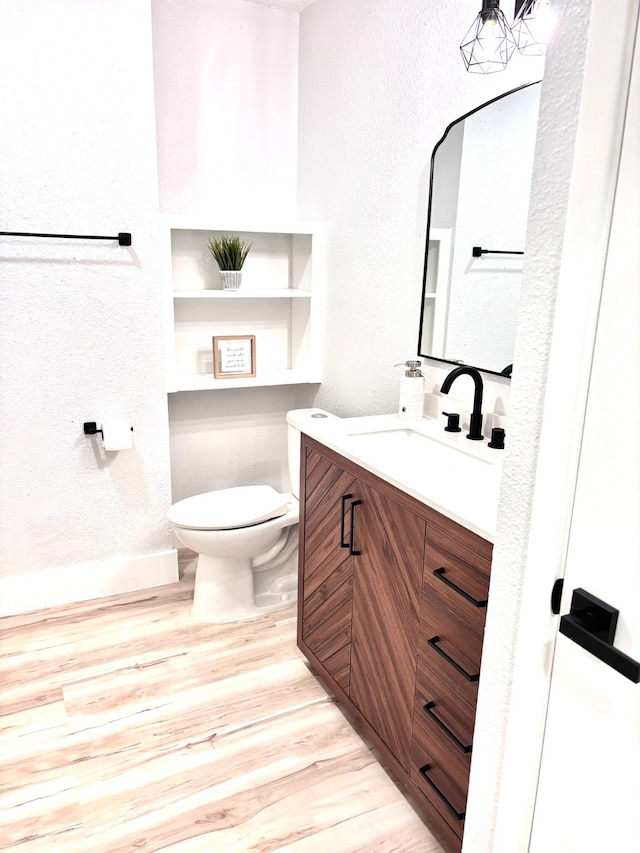 bathroom with wood-type flooring, toilet, and vanity