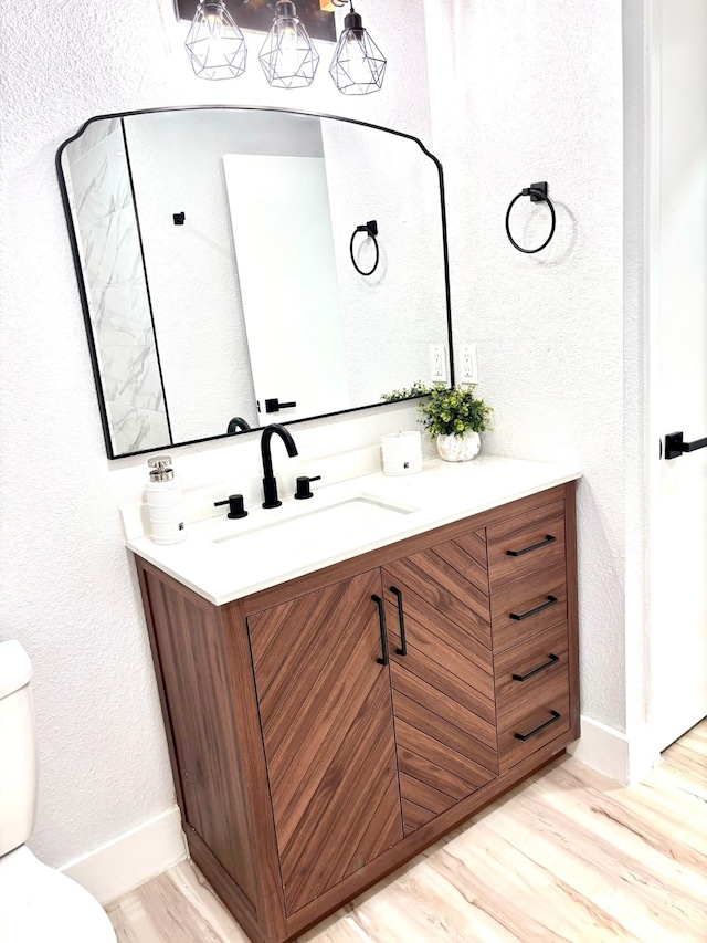 bathroom featuring wood-type flooring, toilet, and vanity