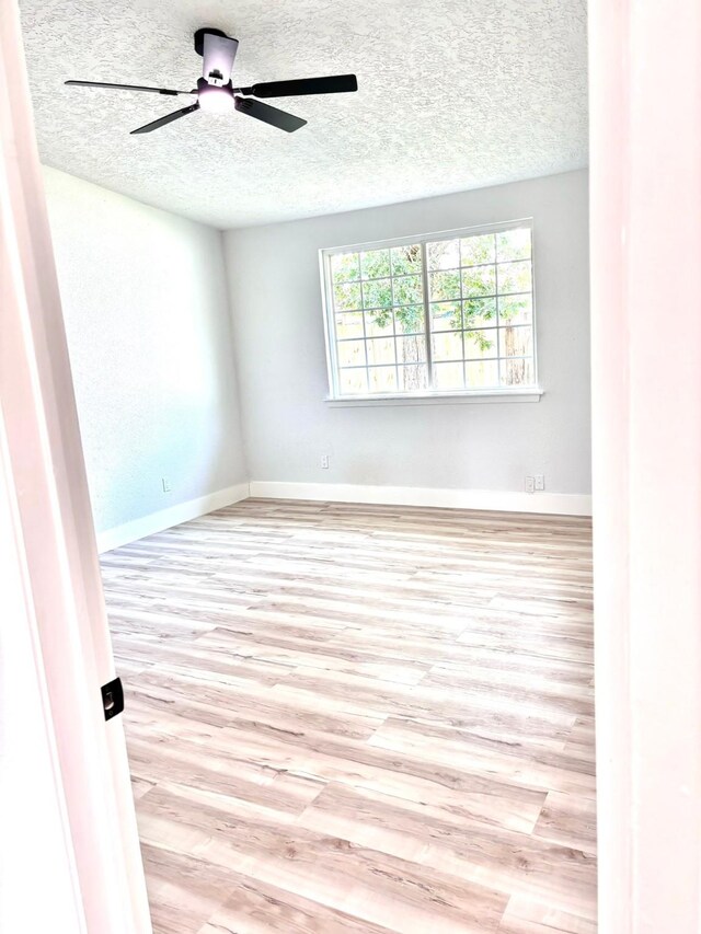 unfurnished room featuring a textured ceiling, ceiling fan, and light hardwood / wood-style floors