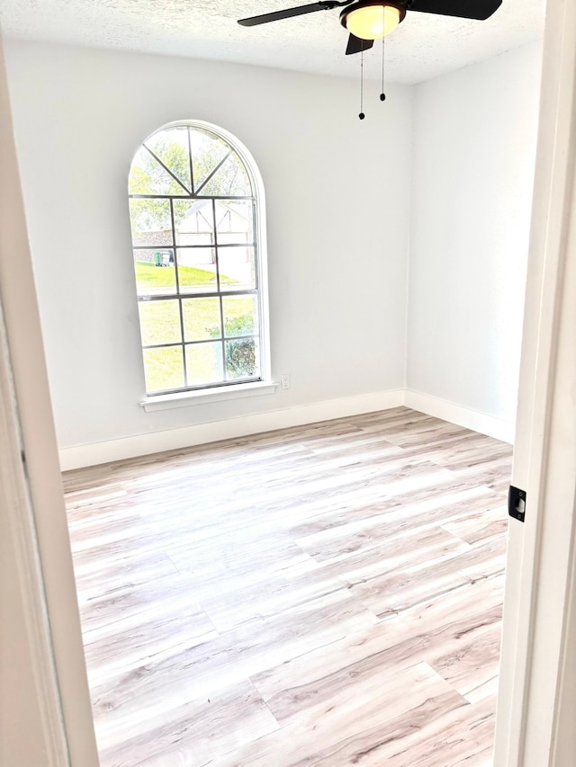 unfurnished room with a wealth of natural light, ceiling fan, a textured ceiling, and light hardwood / wood-style floors