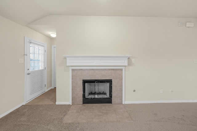 unfurnished living room with light colored carpet, vaulted ceiling, and a tiled fireplace