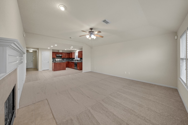 unfurnished living room featuring light carpet, a premium fireplace, and ceiling fan