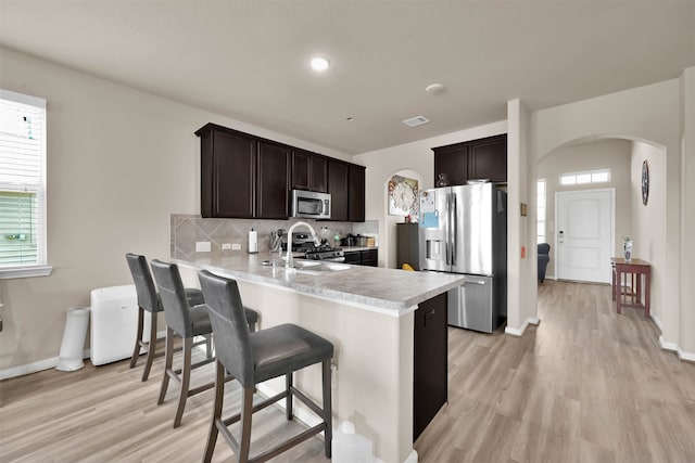 kitchen featuring a breakfast bar, dark brown cabinets, sink, kitchen peninsula, and appliances with stainless steel finishes