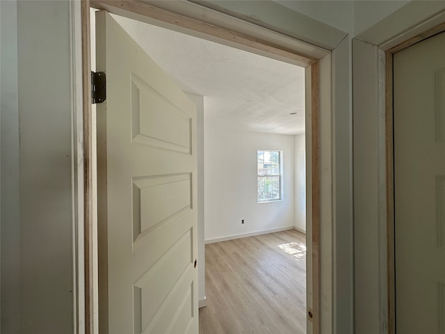 corridor with light hardwood / wood-style flooring and a textured ceiling