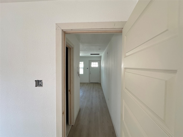 hall with a textured ceiling and wood-type flooring