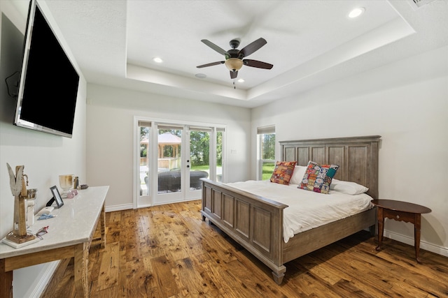 bedroom featuring a tray ceiling, ceiling fan, and light hardwood / wood-style flooring