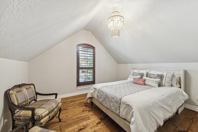 bedroom with lofted ceiling, an inviting chandelier, wood-type flooring, and a textured ceiling